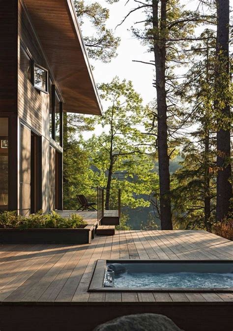 A Hot Tub Sitting On Top Of A Wooden Deck Next To A Forest Filled With