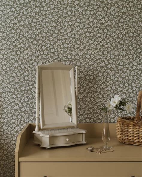 A Dresser With A Mirror And Vase On It Next To A Wallpapered Wall