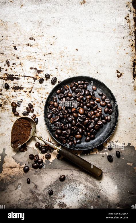 Roasted Coffee Beans In A Pan With A Spoonful Of Ground On Rustic