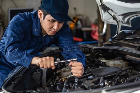 Mecánico En Uniforme Tumbado Y Trabajando Bajo El Coche En El Garaje De