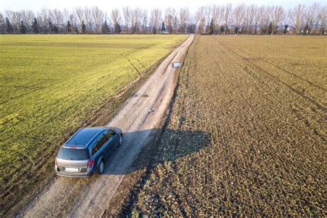 Aerial View Of Car Driving By Straight Ground Road Through Green Stock