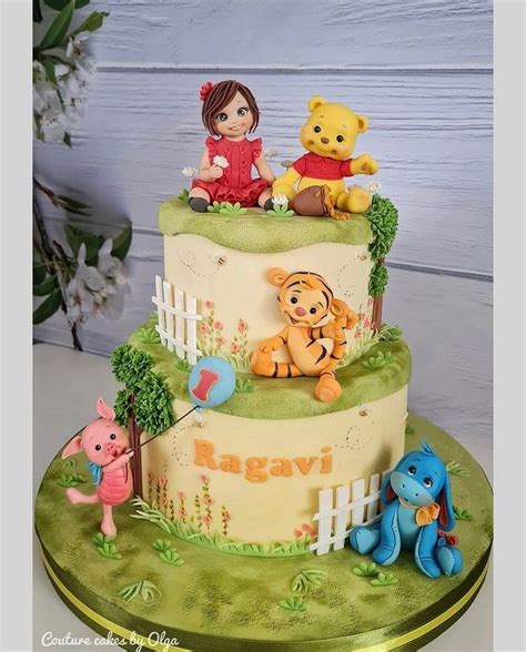 A Three Tiered Cake With Winnie The Pooh Figurines On Top