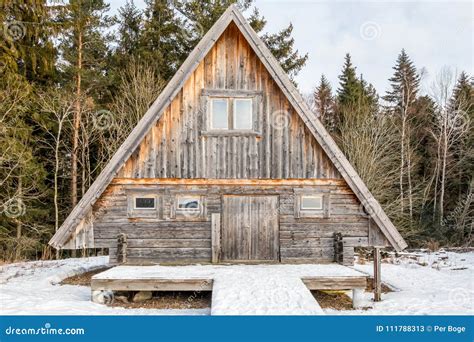 Weathered And Aged Log Cabin Surrounded By Trees And Snow Stock Image