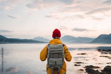 Back View Of Male Tourist With Rucksack Standing On Coast In Front Of