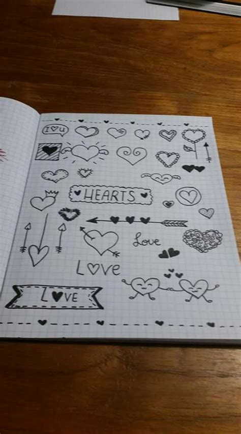 An Open Notebook With Hearts And Arrows Drawn On The Pages Sitting On