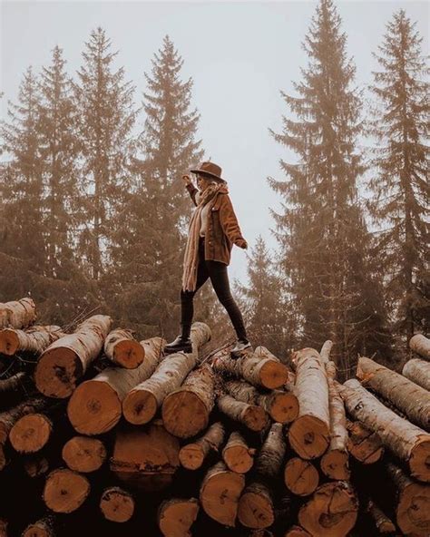 A Man Standing On Top Of A Pile Of Logs