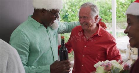 Happy Group Of Diverse Senior Friends Welcoming In Doorway At Christmas