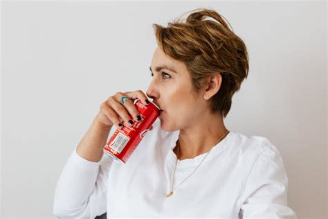 Thoughtful Woman Drinking Coke Near White Wall · Free Stock Photo