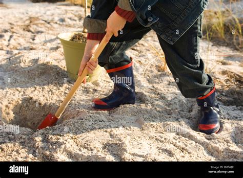 Boy digging hole in sand Stock Photo - Alamy