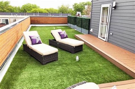 Two Lounge Chairs On Top Of A Green Grass Covered Roof Terrace With