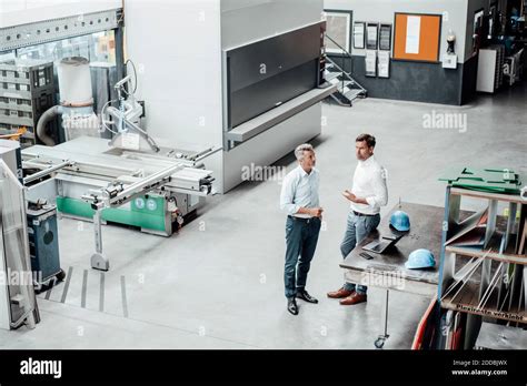 Mature Businessmen Discussing While Standing In Manufacturing Industry
