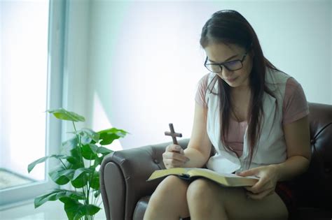 Mulheres asiáticas lendo e rezando cruz de madeira em casa Foto