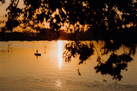 Free Picture Silhouette Of Person Standing In Boat In Distance In Sunset