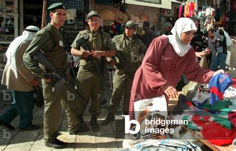 Image of Israeli Border-police patrol past a Palestinian woman in the Old