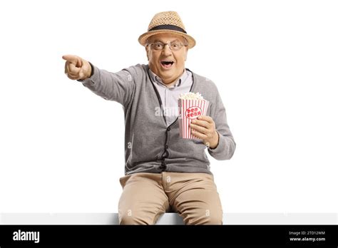 Excited Elderly Man Sitting On A Panel With Popcorn And Pointing