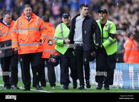 A pitch invader is escorted by police off the pitch Stock Photo - Alamy