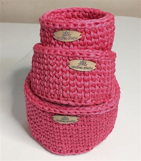 Three Pink Crocheted Baskets Stacked On Top Of Each Other One With Two