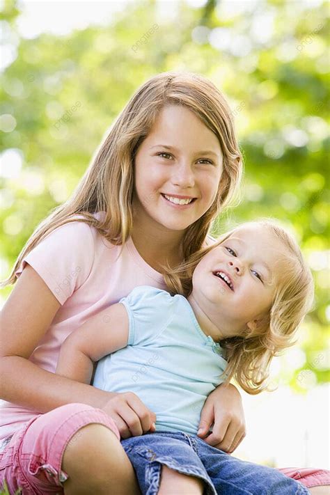 Two Sisters Sitting Outdoors Smiling Outdoors Day Embracing Photo