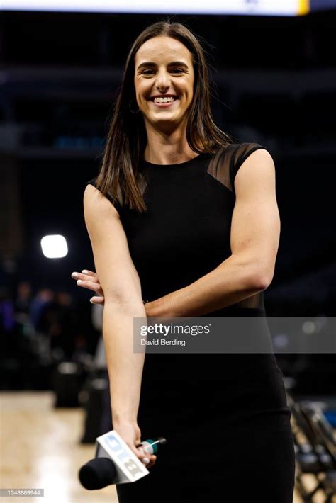 A Smiling Woman In A Black Dress Is Standing With Her Arms Crossed