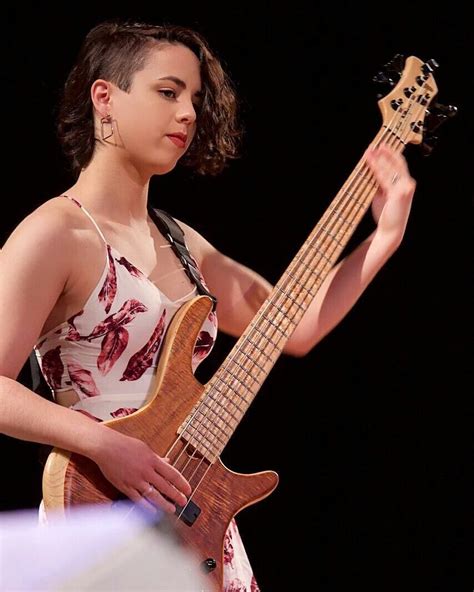 A Woman Holding A Bass Guitar In Her Right Hand