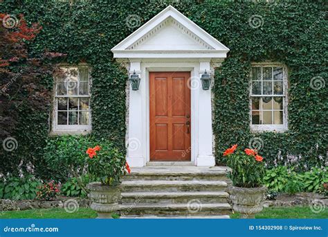 Vine Covered Entrance To White Painted Brick House With Arched Front