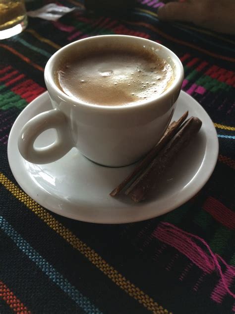 There Is A Cup Of Coffee And Some Cinnamon Sticks On The Saucer Next To It