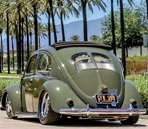 An Old Green Car Parked In Front Of Palm Trees