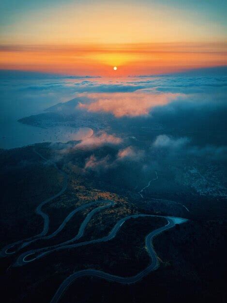 Um pôr do sol sobre o oceano uma estrada sinuosa e o sol se pondo