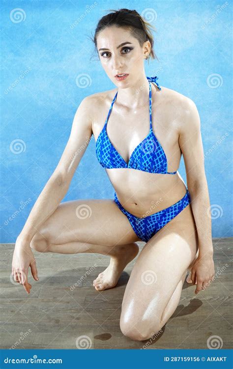 Beautiful Wet Oiled Woman Kneels In Blue Bikini In Studio Stock Photo Image Of Swimmer Poses