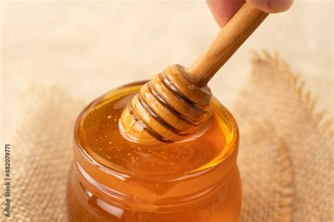 Golden Organic Honey In A Jar With A Wooden Stick Closeup Concept Of