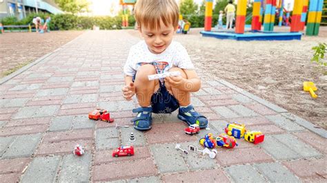 Menino Pequeno Da Crian A Que Senta Se Na Terra No Parque E Que Joga