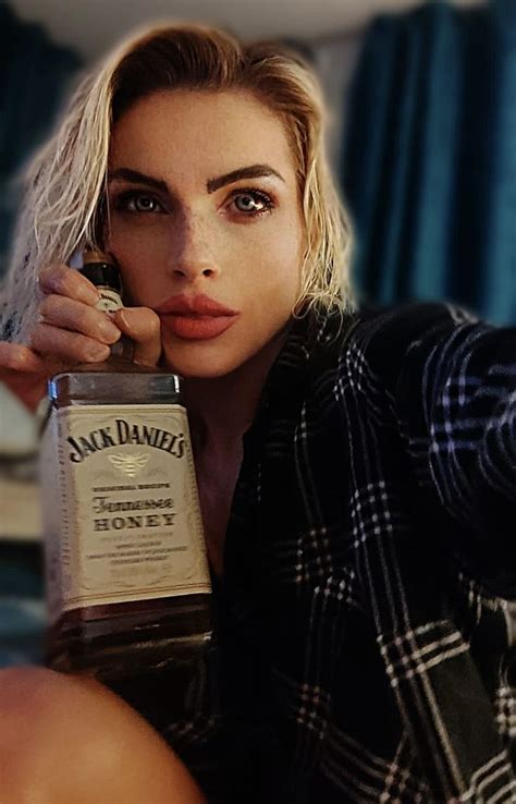 A Woman Holding A Bottle Of Whiskey In Her Right Hand And Looking At