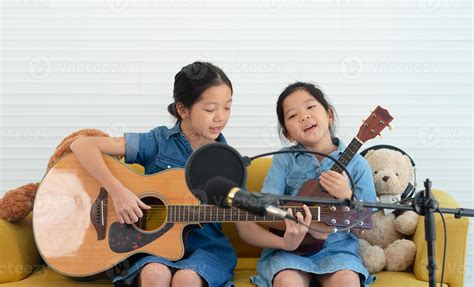 Older And Younger Sisters Kids Singing Song While Playing Guitar And