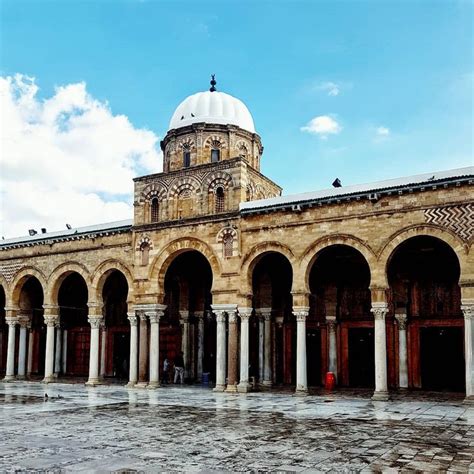 An Old Building With Pillars And Arches In Front Of A Blue Sky Filled