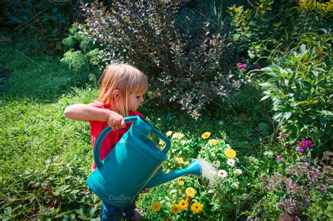 kid watering flowers in garden | People Images ~ Creative Market