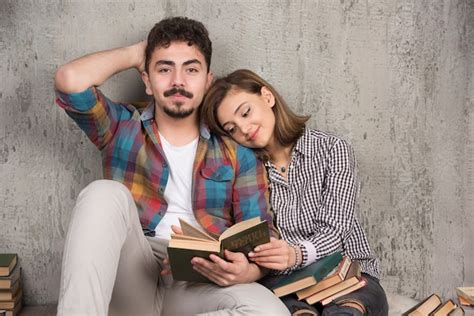 Jeune Couple Souriant Assis Sur Le Sol Avec Des Livres Photo Gratuite