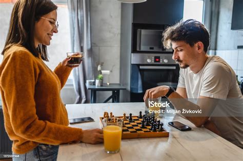 Two People Young Man And Woman Husband And Wife Playing Chess Board Game At The Table In The