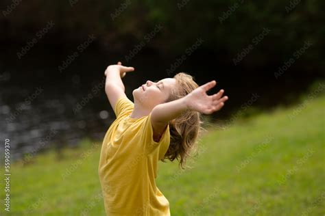 Foto De Peaceful Kid With Raised Hands Meditating Feeling Calm