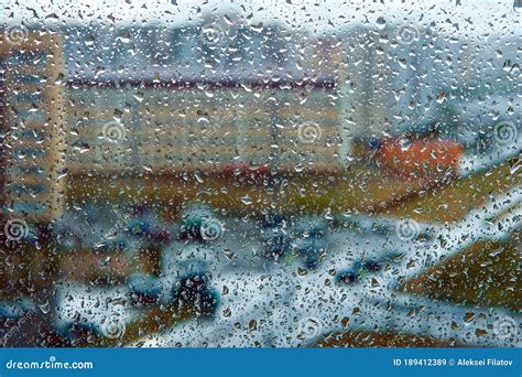 Rain Falls On The Surface Of Window Panes With A Cloudy Background