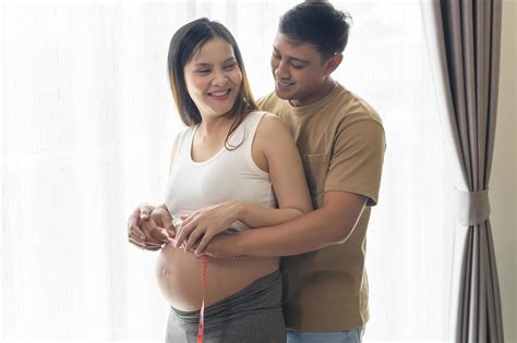 Young pregnant woman measuring belly centimeter, healthcare and ...