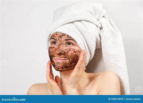 A Beautiful Young Woman With A Bath Towel On Her Head And A Coffee Mask