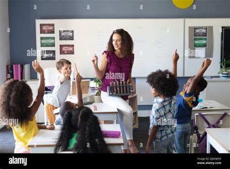 Multiracial Elementary Students Raising Hands While Female Caucasian