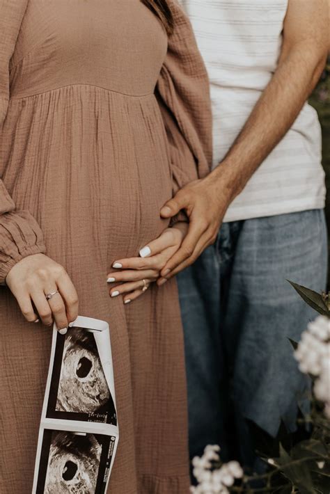 Man Holding Womans Hand Over Her Belly Over Her Pink Dress In The