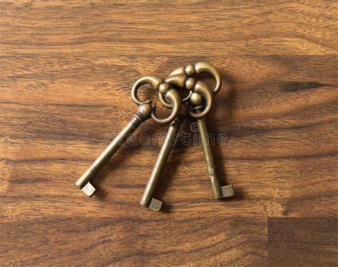 Three Identical Bronze Keys Laying In A Wooden Surface Stock Image