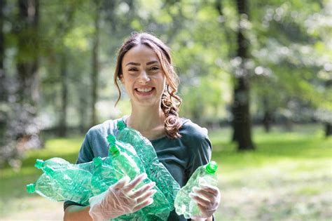 Smiling Female Environmentalist Collecting Plastic Bottles At Park