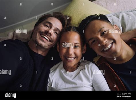 Directly Above Portrait Of Smiling Gay Couple Lying Down With Daughter At Home Stock Photo Alamy