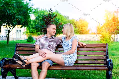 Young Couple Man And Woman Sitting On A Bench Hugging In Park Ribbon