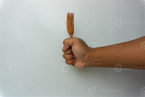 Hand Holding Wooden Spoon And Fork Isolated On White Background