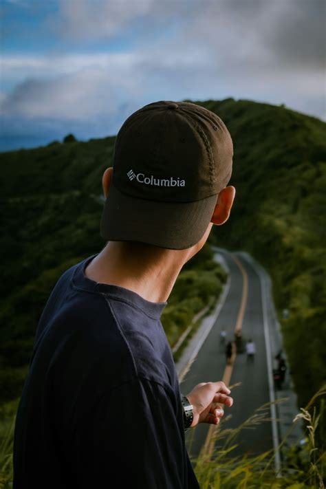 Man In Black Crew Neck Shirt Wearing Black Cap Standing On Road During