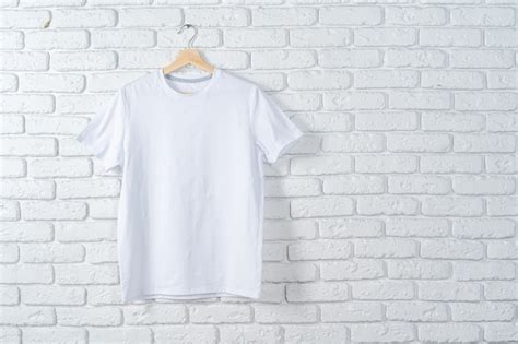 Camiseta Blanca Colgada En La Percha Contra La Pared De Ladrillo Foto